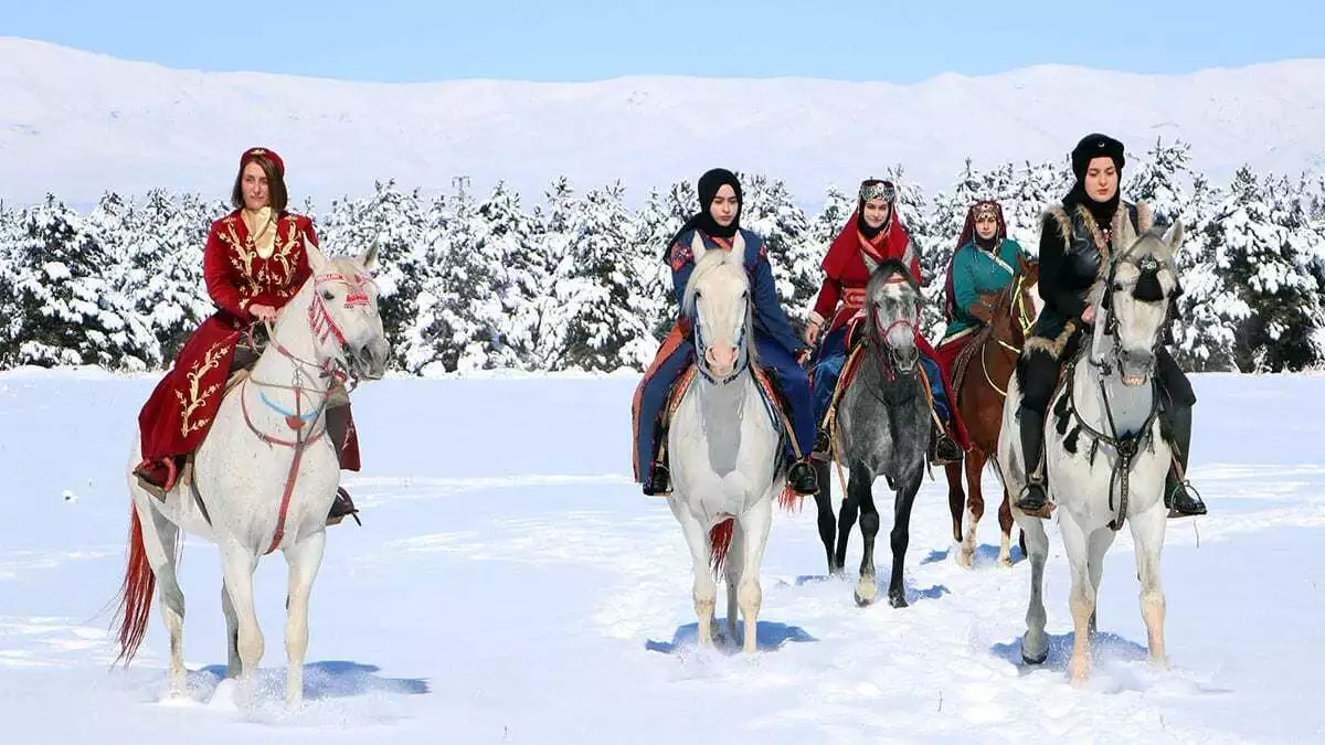 Rengarenk yöresel kıyafetlerle atlarını karlı zeminde dört nala süren kadınlar, dronla havadan görüntülendi.