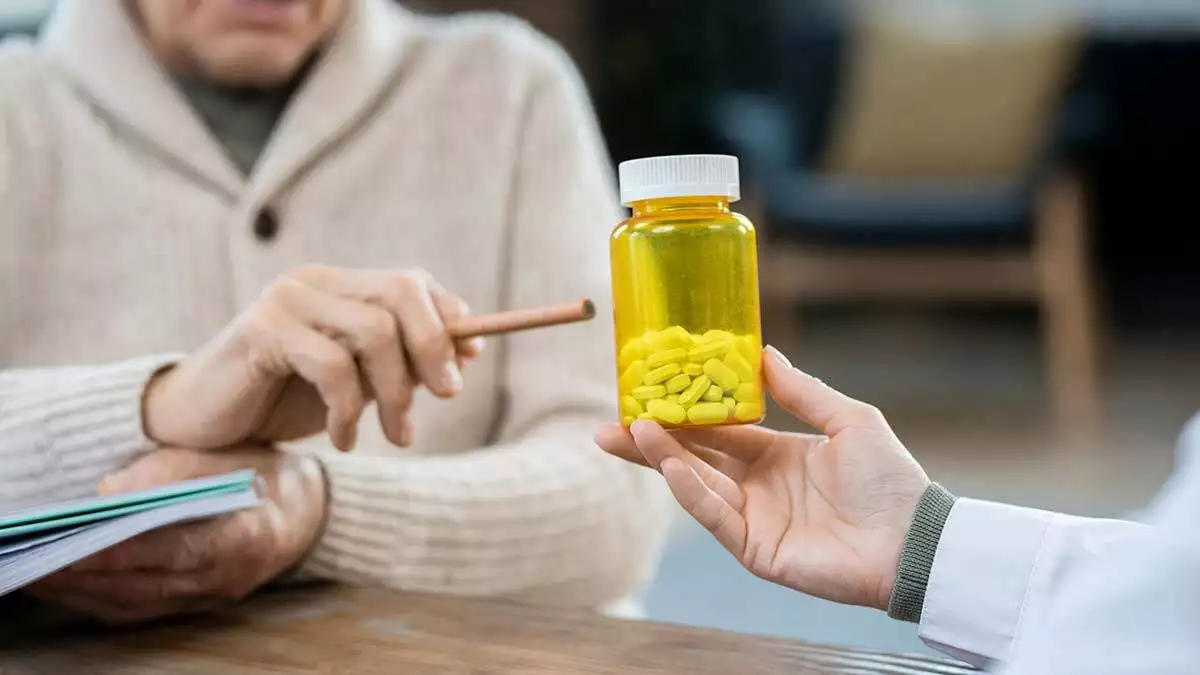 Hand senior man casualwear pointing bottle pills held by female doctor sitting front patient giving medical consultation - yazarlar - haberton