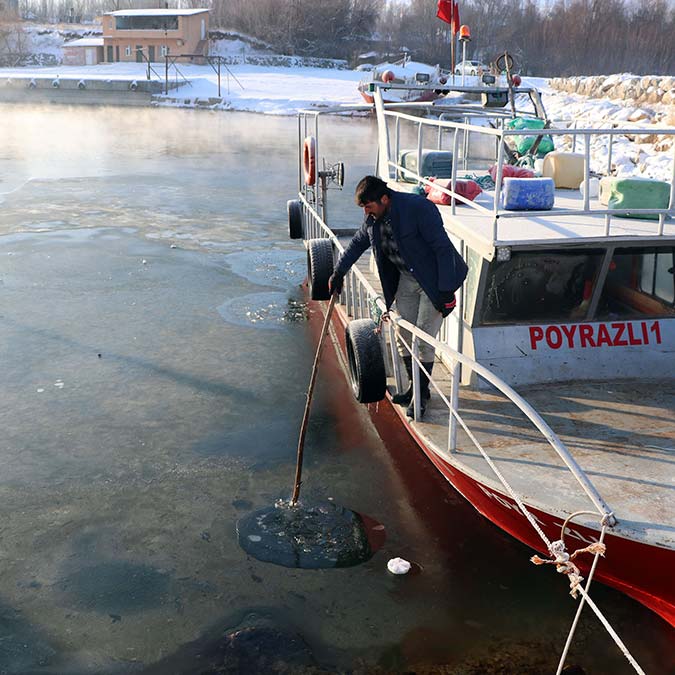Gevaş ilçesi Dereağzı Mahallesi'nde balıkçılar, teknelerinin güzergahındaki buz kütlelerini demir ve tahta çubuklarla kırdıktan sonra göle açılıyor.