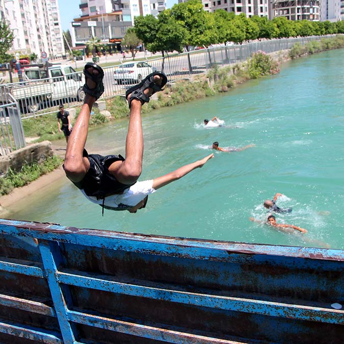 Adana'da termometreler 42 dereceyi gösterirken, sıcaktan bunalanlar, ağaç gölgelerinde oturdu. Gençler ise tehlikeye rağmen sulama kanalına girip, serinlemeye çalıştı.