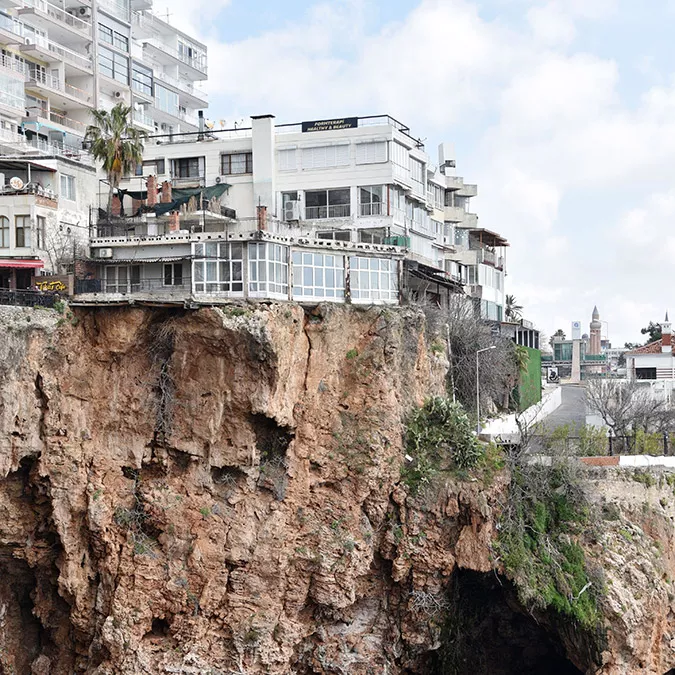 Antalya'da falezlerdeki binalara sonradan yapılan eklentilerin demirle kayalıklara sabitlenmeye çalışıldığı, çatlama nedeniyle yarık oluşan kayanın üzerindeki evin bir bölümünde kayma olduğu ve balkonun çatladığı görüldü.