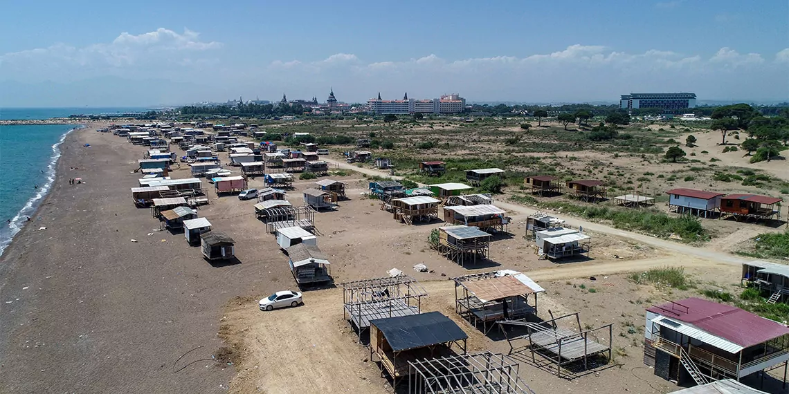 Antalya'da, 5 yıldızlı otellerin yanı başına kurulan, nesli tükenme tehlikesindeki deniz kaplumbağalarının yuvalama alanı olması nedeniyle verilen yıkım kararı defalarca ertelenen çardak kentte yaşayanlar, barakalarına güneş panelleri bağladı.