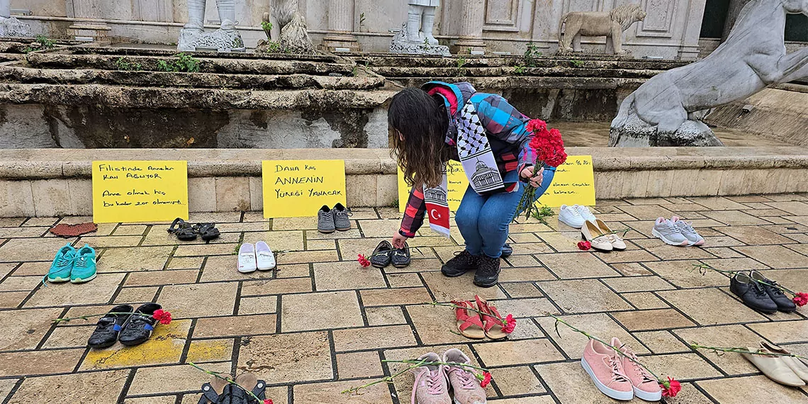 İsrail saldırılarında filistin'deki anne ve çocuk ölümlerine dikkat çekmek isteyen özge yalın yılmaz (31), kentin en işlek parkında kadın ayakkabıları dizip, karanfil koyarak farkındalık oluşturmaya çabaladı.