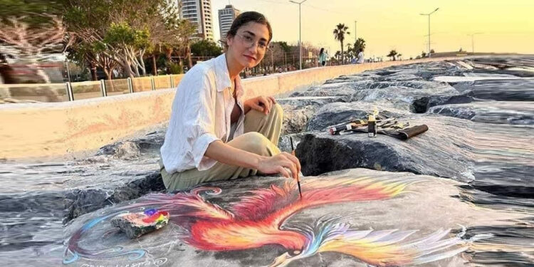 Depremzede ressam sahildeki kayalara renkli figürler çiziyor