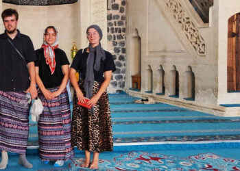 Ulu Camii'yi ziyaret eden erkek turistler, kadınlar için ayrılan etekleri giydi