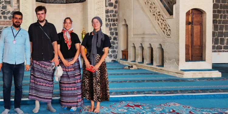 Ulu Camii'yi ziyaret eden erkek turistler, kadınlar için ayrılan etekleri giydi