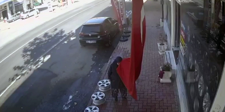 Yaşlı kadının iş yeri önündeki bayrağı öpmesi kamerada