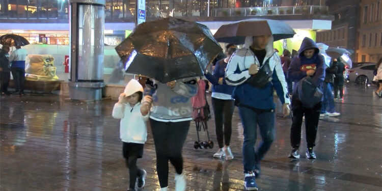 Taksim Meydanı'nda yağmura yakalananlar otobüs durağına sığındı