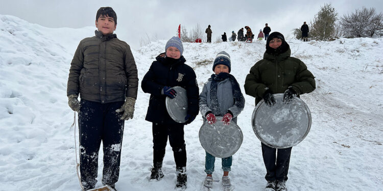 Çocuklar fırın tepsisi, leğen, poşet ve kızakla kaydı
