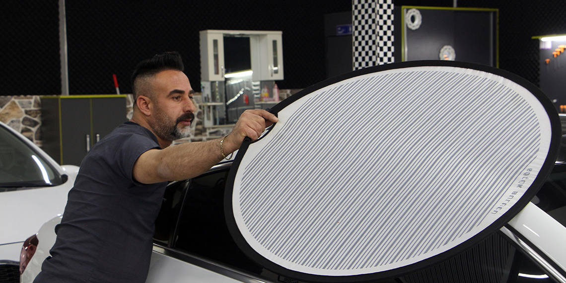 Kaporta ustası, araçları doktor kıyafeti giyerek tamir ediyor