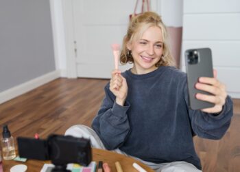 Image of stylish young woman, social media influencer, taking pictures on mobile phone, doing makeup tutorial for followers online, recording video vlog in her bedroom, showing brush. SSUCv3H4sIAAAAAAAACpySyW7DIBCG75X6DhbnWMI2dkhfpephWByjEIgAp6qivHtZ7IheK3Fgvpn5Z4HH+1vTIAZecfTRPJIVbaX16oODoKyJGB827qQR0tXk7oYJ1wBUbUmhgnUKdA0ZBL4YuMoIzap1ws/sRD5AWL30qZcNcQjyHDUKfEmUhj+L3eyO7IwZ0YXQoWJ+ZZntqIj/K7Ncvl4Dn6XhP7nhahAntYQyyNYjEuPMOoJpywAfWzKdSEvxkbacyn7C7NQJMucqRRpdvoN013oVsAplqy3cLQedAoaqMqgbOPiTd3OKK3OuiA1LfsddidvVBJemeA2PtLU3YDq90hzLyJ0v4H0MFzuvavP4a+y1qmNsyDvYVJGIj5nMbhjGcTrSYTiOtI8HbwHlAywq6uR2dqFo84sS9VQqdYDIifAJE2jpLOJW565voZ/ijRHJ5TzRsZNxq89fAAAA//8DAIlXss7pAgAA