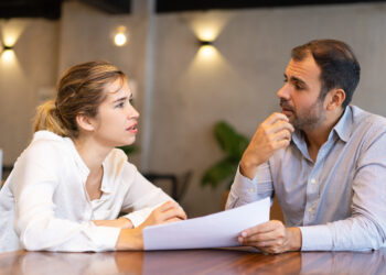 Serious business professional discussing report. Two colleagues studying papers and talking in meeting room. Business meeting concept