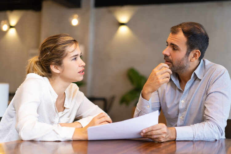 Serious business professional discussing report. Two colleagues studying papers and talking in meeting room. Business meeting concept