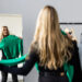 Young woman looking into mirror near wardrobe at home