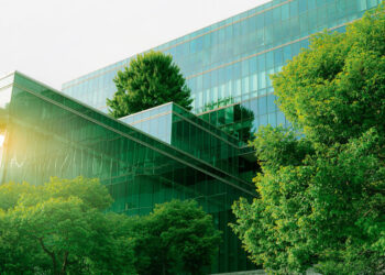 Sustainble green building. Eco-friendly building. Sustainable glass office building with tree for reducing carbon dioxide. Office with green environment. Corporate building reduce CO2. Safety glass.