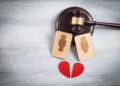 Concept of divorce. Male and female wooden symbols, red heart and judge gavel