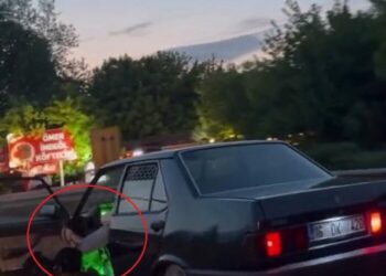 Otomobilinin sol ön kapısını açıp, ayağıyla tutarak trafikte ilerledi