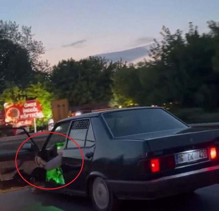 Otomobilinin sol ön kapısını açıp, ayağıyla tutarak trafikte ilerledi