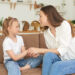 The little girl complains to her mother and cries. A young woman calms her daughter on the couch at home.