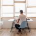 young handsome man in casual outfit sitting at table working on laptop, freelancer at home, view from back