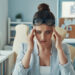 Stressed young woman in smart casual wear keeping head in hands while sitting in the office