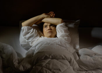 Woman with insomnia lying in bed with open eyes