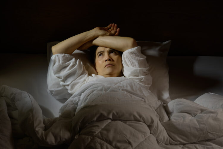 Woman with insomnia lying in bed with open eyes