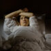 Woman with insomnia lying in bed with open eyes