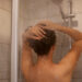 Back view portrait of slime woman with naked shoulders taking shower, posing backwards in bathroom, personal hygiene, morning procedures, hair care and refreshment.
