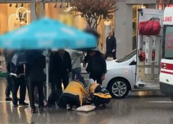 Otomobilin çarptığı yaralıyı yağmurdan korumak için şemsiye tuttular