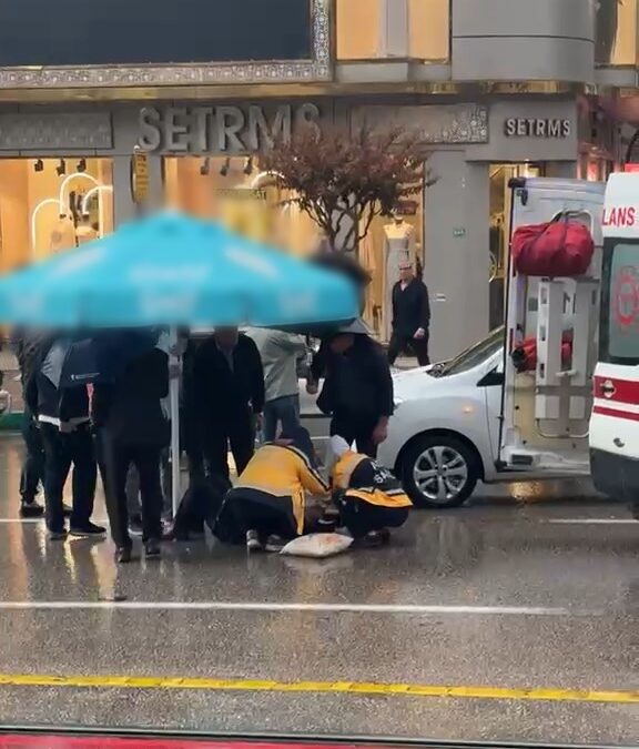 Otomobilin çarptığı yaralıyı yağmurdan korumak için şemsiye tuttular