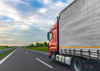 A red cargo truck drives on a highway beside a gray trailer, with open lanes and countryside visible. Useful for freight transport articles, logistics marketing, trucking content, and road infrastructure materials. SSUCv3H4sIAAAAAAAAA41Py46DMAz8F5+DFGihaX6l6sEhLrUKpEpMqxXKv69Cqfa6txnb8/AK7MFCc75hdzK66siYqq5vdWWocVXrHHp3ojPqBhR4FAJbH45N15m2M8f2YLTWWoHDxD3YFXgclyQRhcMMViuINHuKGyTPEiLjCFZnBUlQlkQJ7JoV9Cg0hMgb//pd1jIHC6AgLa6ArP45uyrAgeb+p/jnUmQk3OIuVwWPt1Cc9uwg91KxwGfknudh77QkCdMHz0GKdkuQ0D/Y7+LPG3dOEmLJguU5BvTk9/XiJhb50kgvpvffdc75F/TyQcyEAQAA