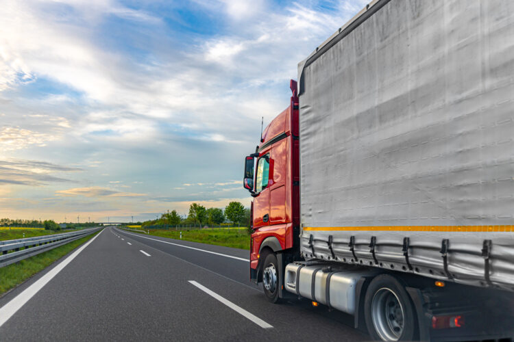 A red cargo truck drives on a highway beside a gray trailer, with open lanes and countryside visible. Useful for freight transport articles, logistics marketing, trucking content, and road infrastructure materials. SSUCv3H4sIAAAAAAAAA41Py46DMAz8F5+DFGihaX6l6sEhLrUKpEpMqxXKv69Cqfa6txnb8/AK7MFCc75hdzK66siYqq5vdWWocVXrHHp3ojPqBhR4FAJbH45N15m2M8f2YLTWWoHDxD3YFXgclyQRhcMMViuINHuKGyTPEiLjCFZnBUlQlkQJ7JoV9Cg0hMgb//pd1jIHC6AgLa6ArP45uyrAgeb+p/jnUmQk3OIuVwWPt1Cc9uwg91KxwGfknudh77QkCdMHz0GKdkuQ0D/Y7+LPG3dOEmLJguU5BvTk9/XiJhb50kgvpvffdc75F/TyQcyEAQAA
