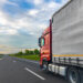 A red cargo truck drives on a highway beside a gray trailer, with open lanes and countryside visible. Useful for freight transport articles, logistics marketing, trucking content, and road infrastructure materials. SSUCv3H4sIAAAAAAAAA41Py46DMAz8F5+DFGihaX6l6sEhLrUKpEpMqxXKv69Cqfa6txnb8/AK7MFCc75hdzK66siYqq5vdWWocVXrHHp3ojPqBhR4FAJbH45N15m2M8f2YLTWWoHDxD3YFXgclyQRhcMMViuINHuKGyTPEiLjCFZnBUlQlkQJ7JoV9Cg0hMgb//pd1jIHC6AgLa6ArP45uyrAgeb+p/jnUmQk3OIuVwWPt1Cc9uwg91KxwGfknudh77QkCdMHz0GKdkuQ0D/Y7+LPG3dOEmLJguU5BvTk9/XiJhb50kgvpvffdc75F/TyQcyEAQAA